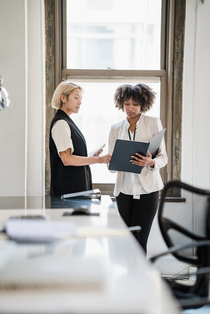 Mastering the First Impression: Your intriguing post title goes here Two businesswomen discussing documents in a modern office setting.